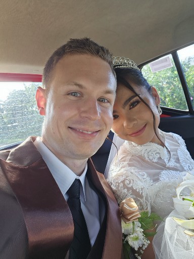 A groom takes a selfie in a car with his new bride