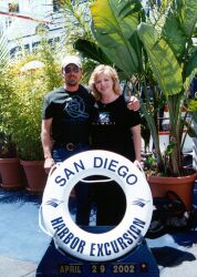 Widowed Christians hug behind a San Diego Harbor sign