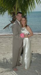 A beautiful Christian couple smile together on the beach under a palm tree