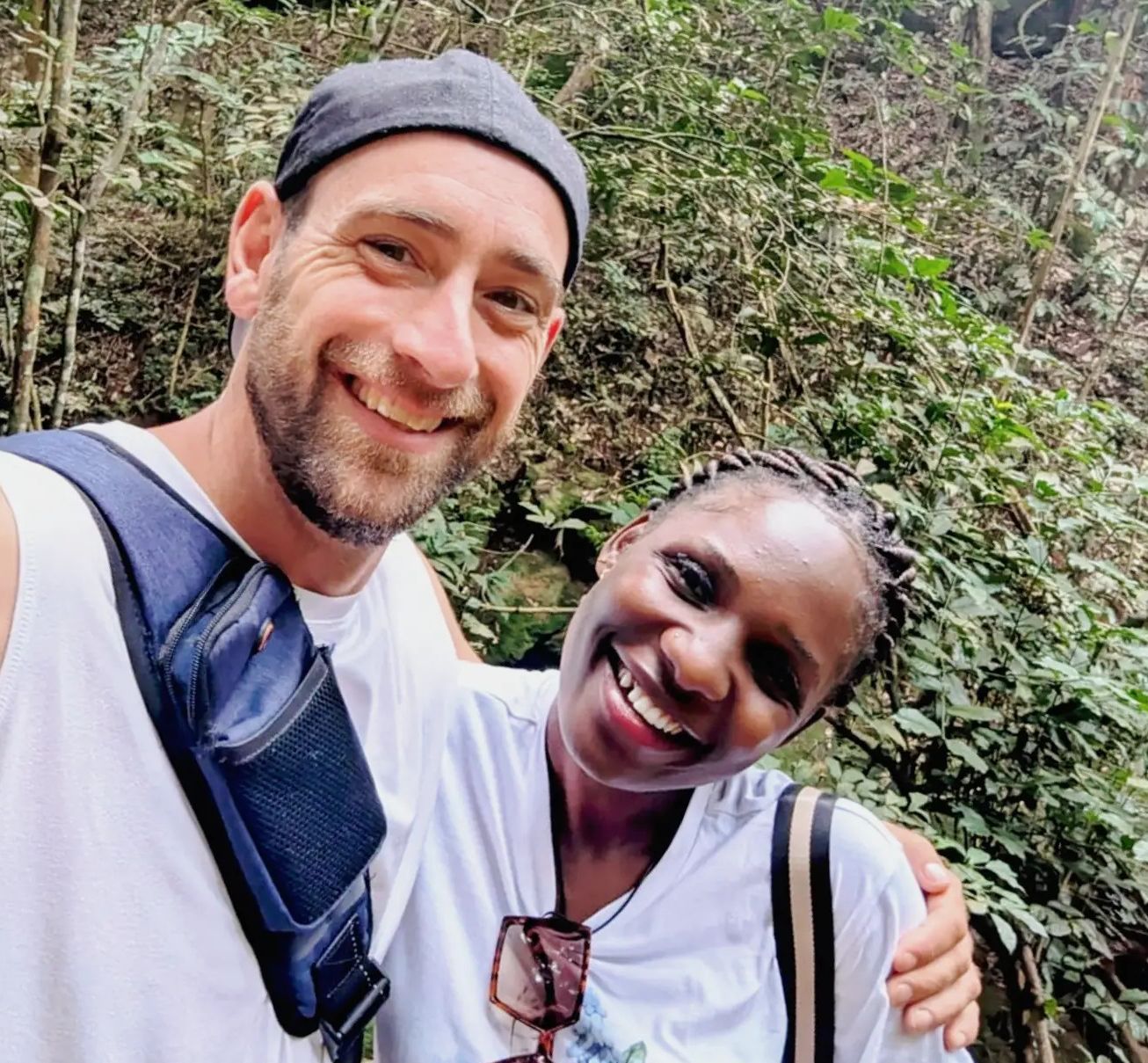 An interracial couple hugs while laughing on a nature walk