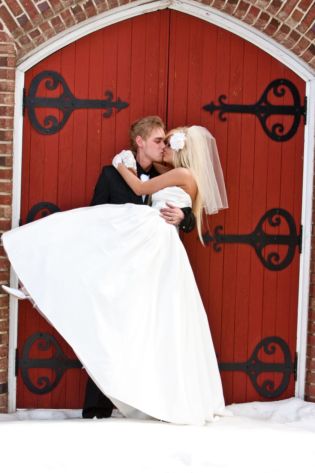 Groom carries his bride while kissing her lovingly