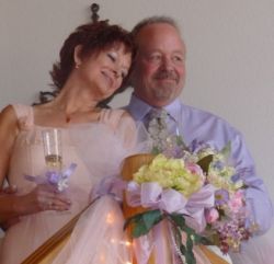 Christian wife looks so peaceful in the arms of her loving husband as she holds her wedding flowers