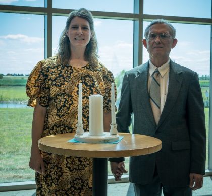 Former Christian singles from Illinois marry and pose in front of wedding candles in front of big glass windows