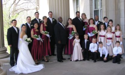 Huge wedding party flanks smiling Christian couple as they pose outside