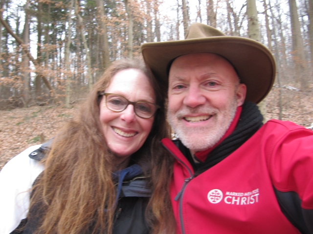 A couple take a selfie and smile while on a walk in the forest