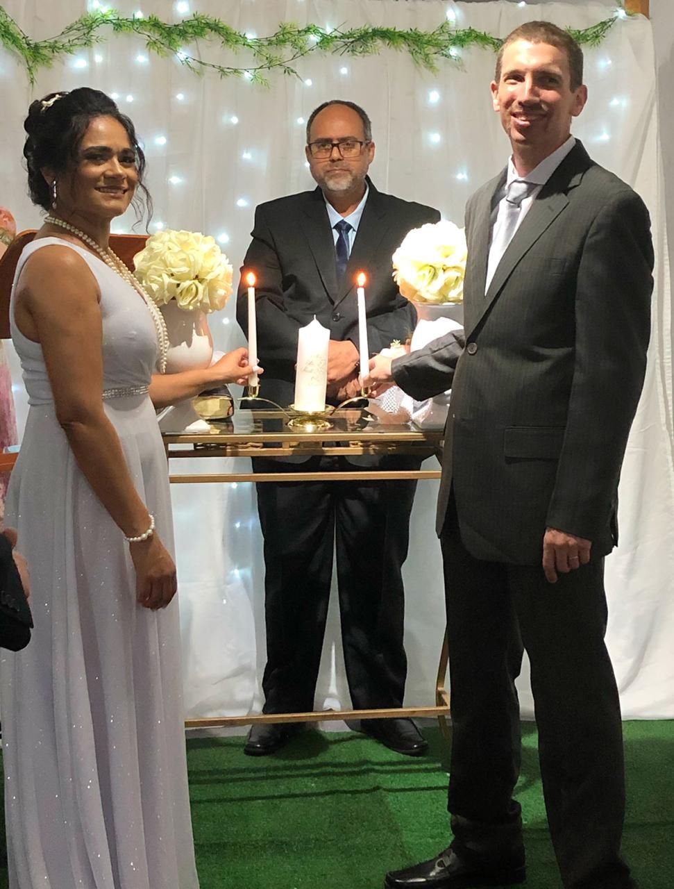 Brazilian bride in white dress lighting wedding candles with American groom