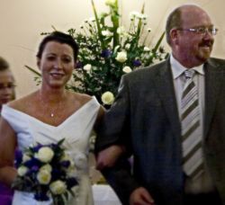 English groom beaming with joy as he walks arm in arm with his beautiful bride