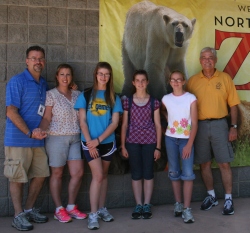 A family poses against a wall outside the zoo