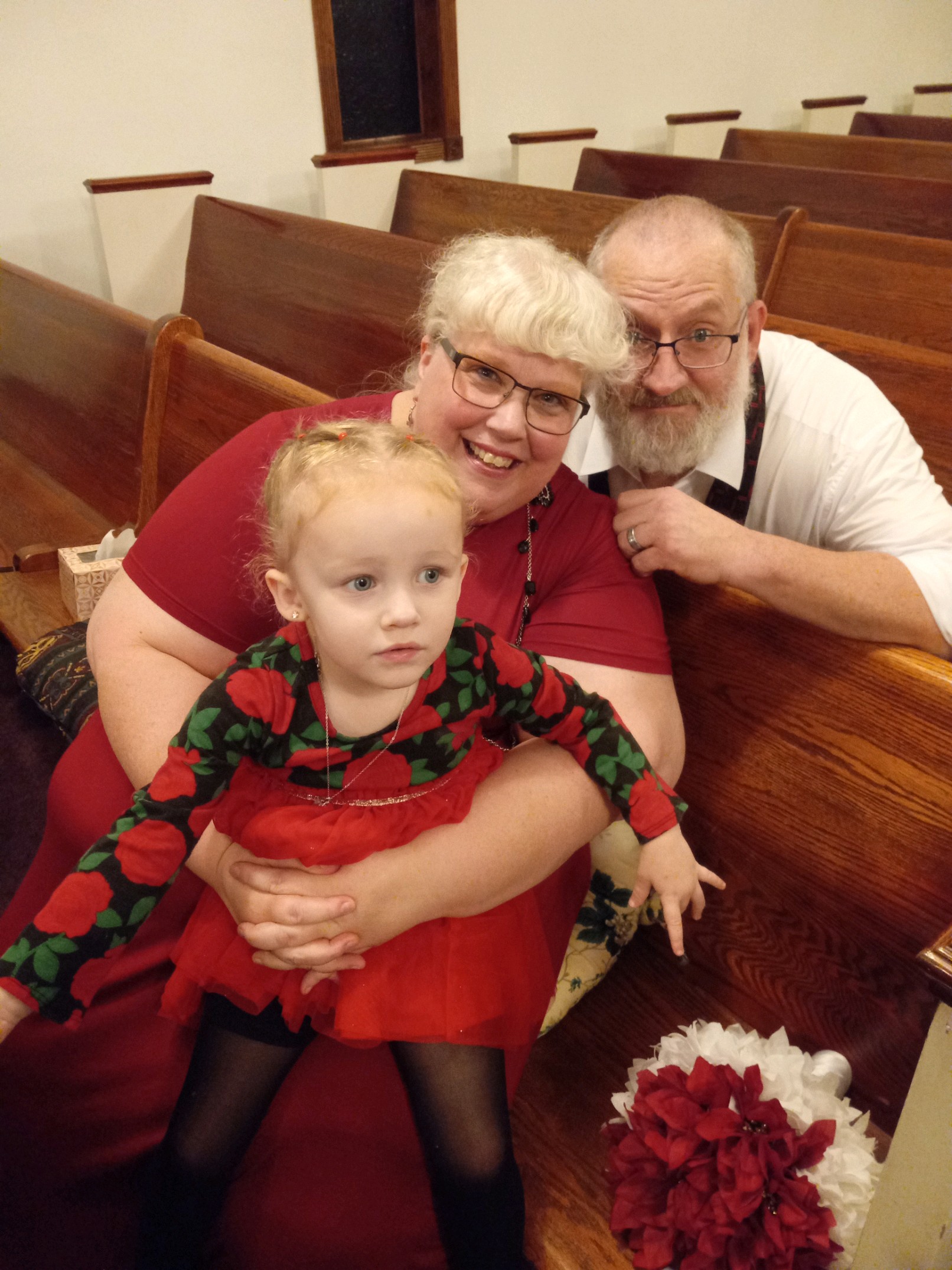 Happily married Christians in church hold a granddaughter while laughing