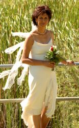 a beautiful bride pose in her wedding dress with flowers in front of a field
