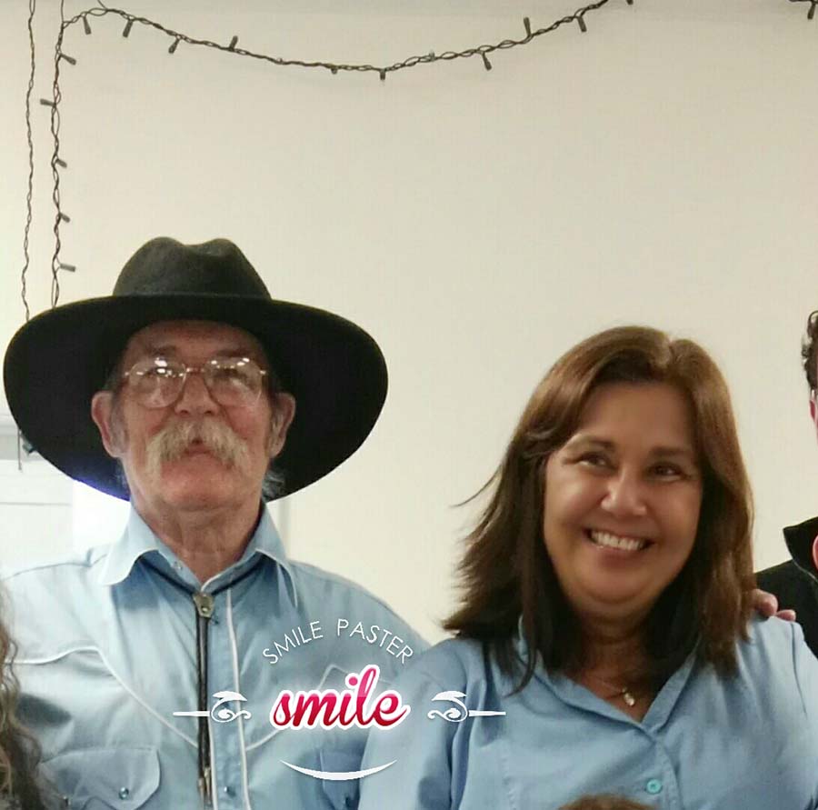 Smiling man in cowboy hat next to his wife who is laughing broadly from ear to ear