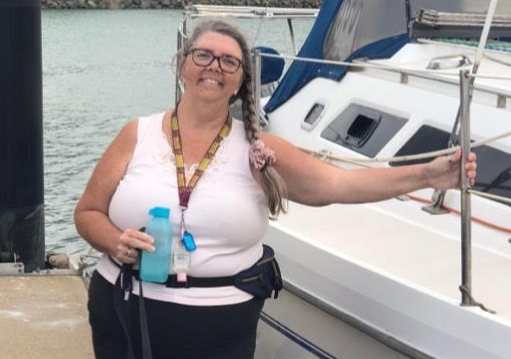 A happy woman poses next to a yacht