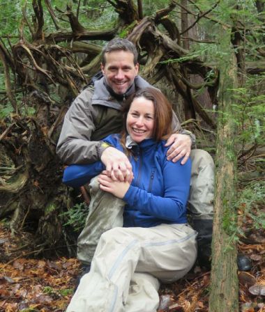 A couple sitting together and hugging in a forest while smiling