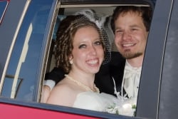 A radiant woman smiles in a car while a smiling man leans over