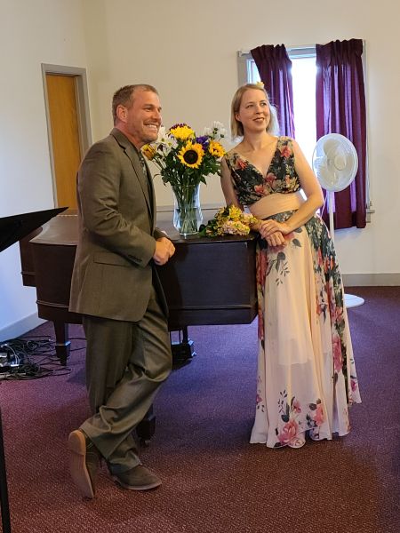 Newlywed Christians posing by piano and smiling