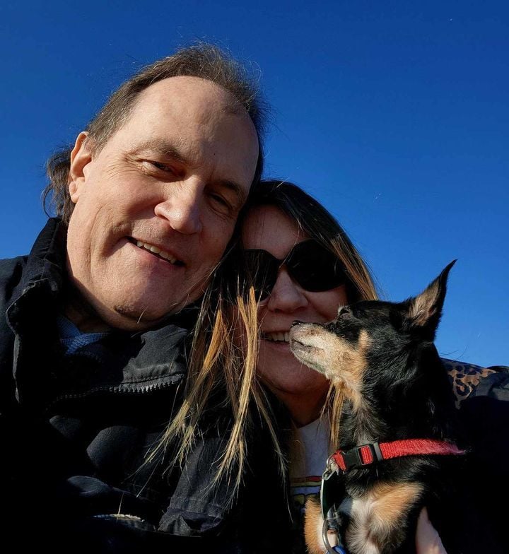 A middle aged Christian couple laugh together while take a selfie outdoors with their dog