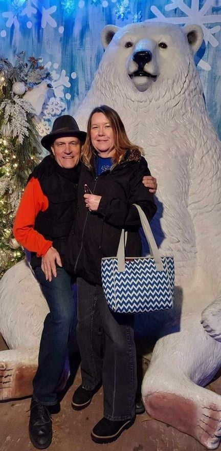 A married Christian couple pose in front of a polar bear at Christmas time