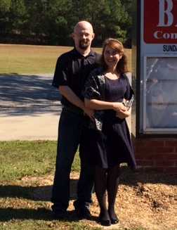 A very happy young Christian couple pose outside church