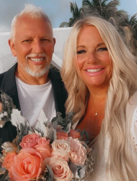 A Christian man beams proudly as his new wife smiles while holding flowers