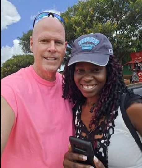 A White Christian man leans in closely to a Black Christian woman wearing a hat while they pose outdoors