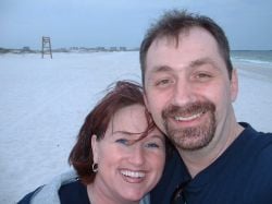 A Christian couple laugh together for a beach selfie