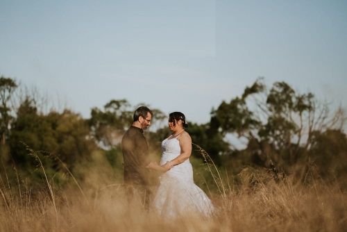 Newlyweds in field talking in background while holding hands