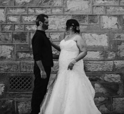 Christian couple wedded outdoors while standing in front of old wall