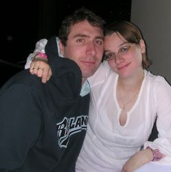 A contented woman in pink holds on to a man in a sweater