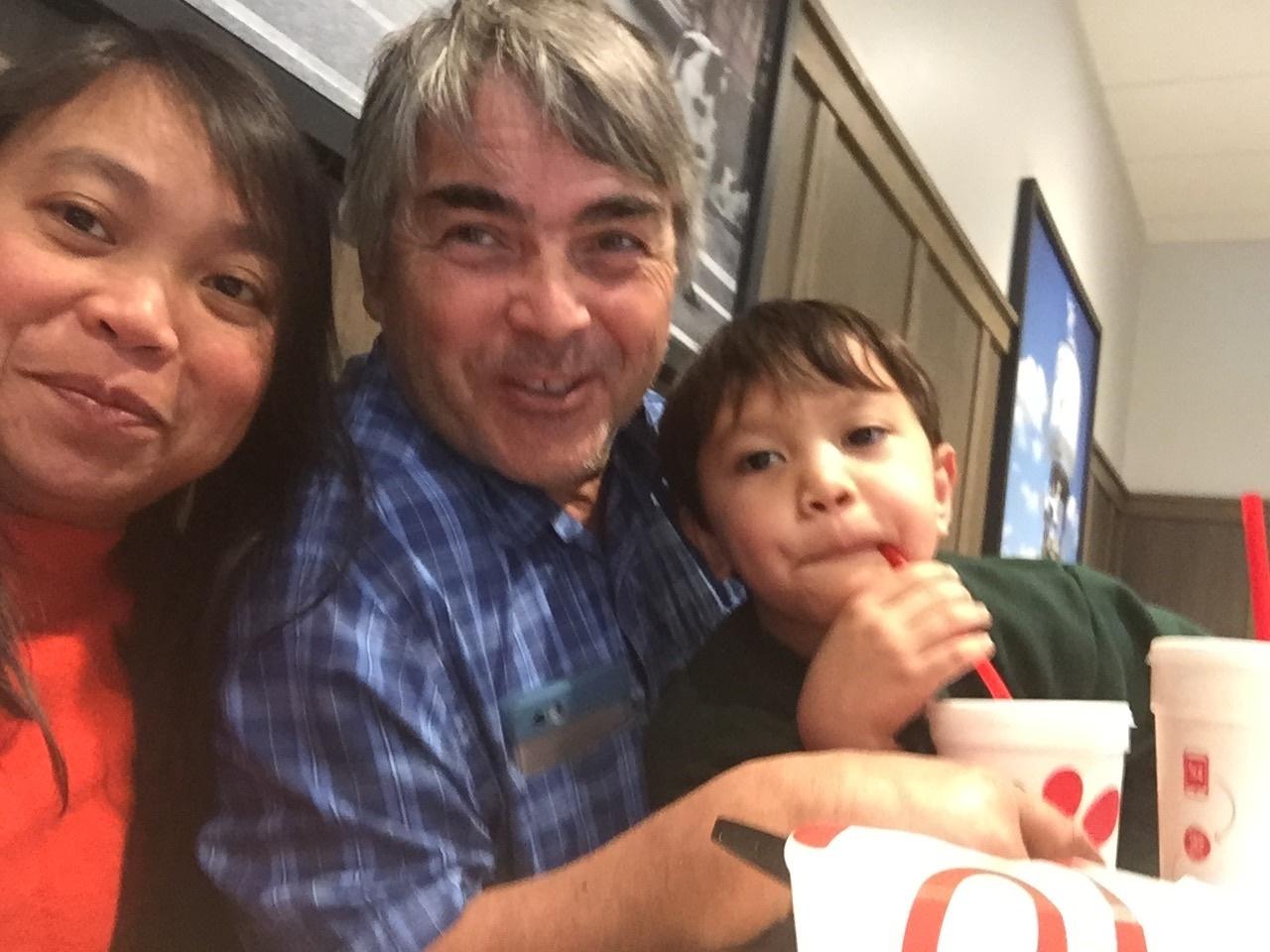 A mixed race couple enjoy a meal out with their son, at a restaurant