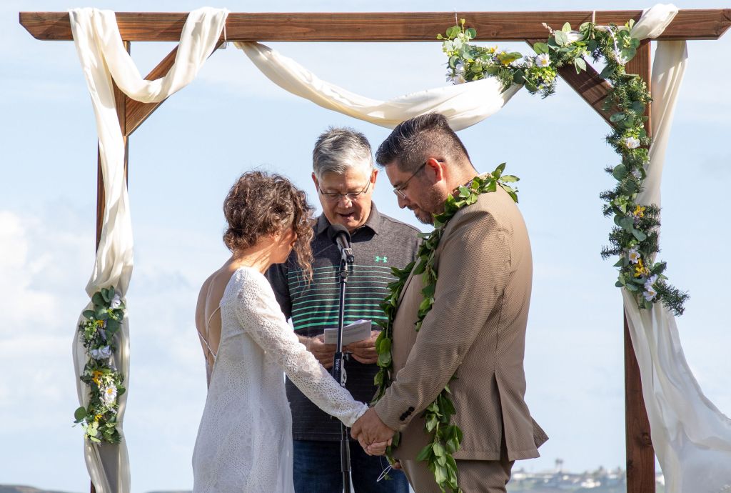 A Christian couple marry outdoors while the minister blesses them