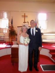 A Christian schoolteacher holds her bridal bouquet while standing next to her new husband