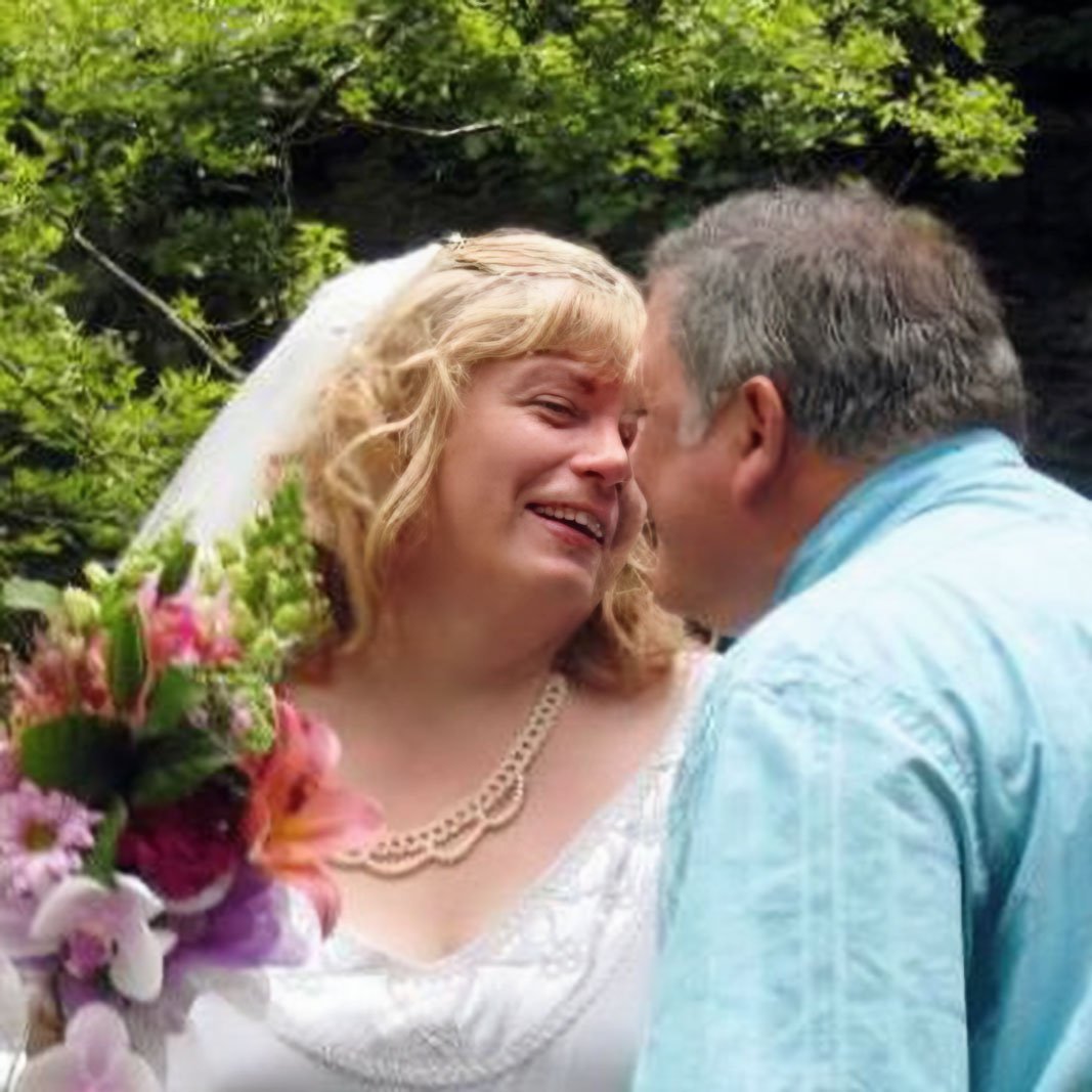 A new bride giggles in delight as her husband leans in to kiss her