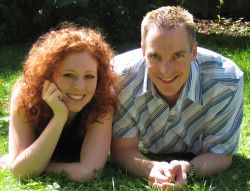 Cute Christian couple giggle together on the grass in the sunshine