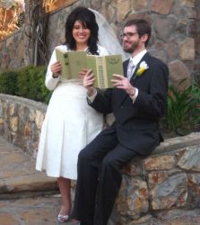 Former singles from California laugh while pretending to read together white seated on a stone wall