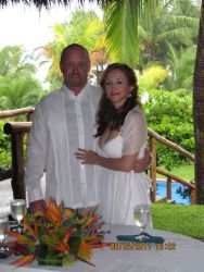 A beautiful Colombian Christian woman hugs her American husband at a tropical wedding