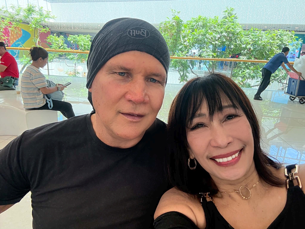 A man with a bandana poses in a mall next to a pretty woman in black