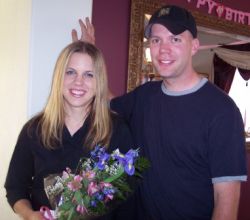 A man's hand seems to come out of his fiancee's head as she laughs and holds flowers