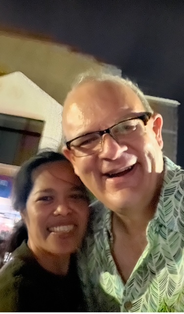 A man smiles broadly with his arm around his new fiancee