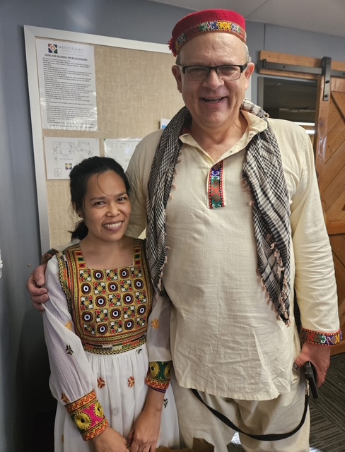 A tall man in Afghan clothing stands next to a much shorter woman