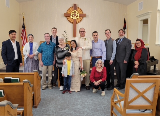 Friends at a wedding all pose with a new bride and groom in a church