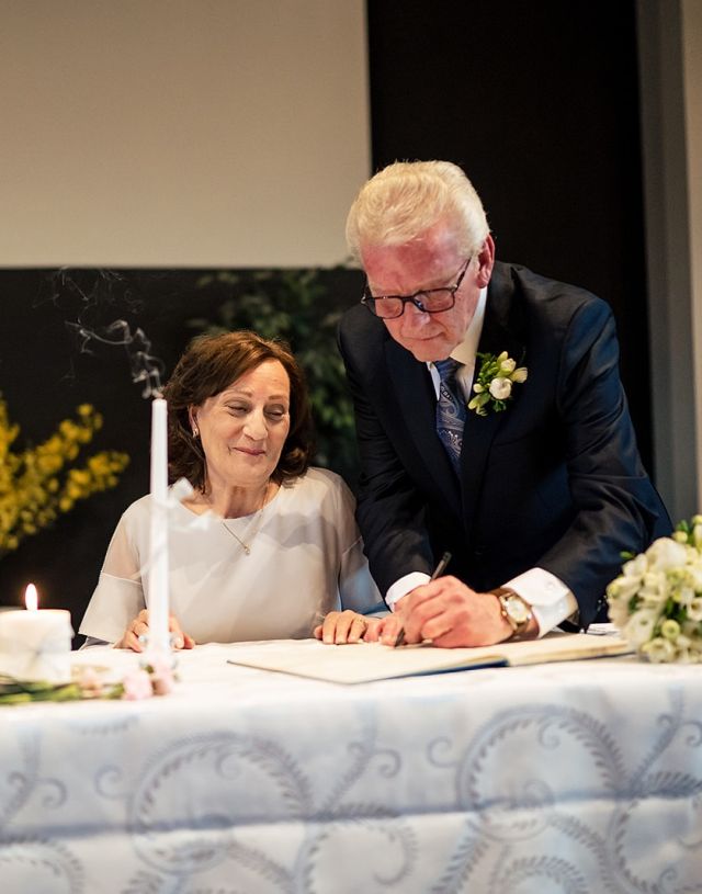 A very happy bride beams with joy as her husband signs the Registry