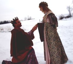 A king on one knee asks for a queen's hand in marriage in the snow