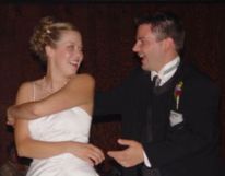 A bride has her hands wrapped around herself trying to grab her husband as they laugh