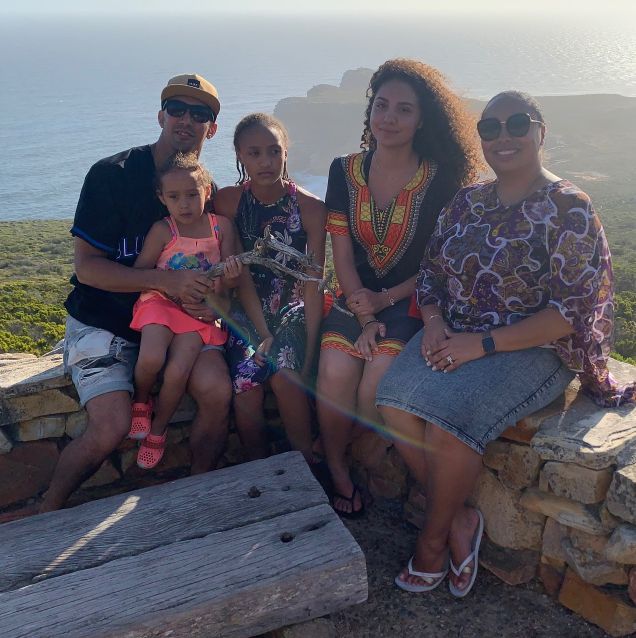 Family looking at camera with ocean and hills in background