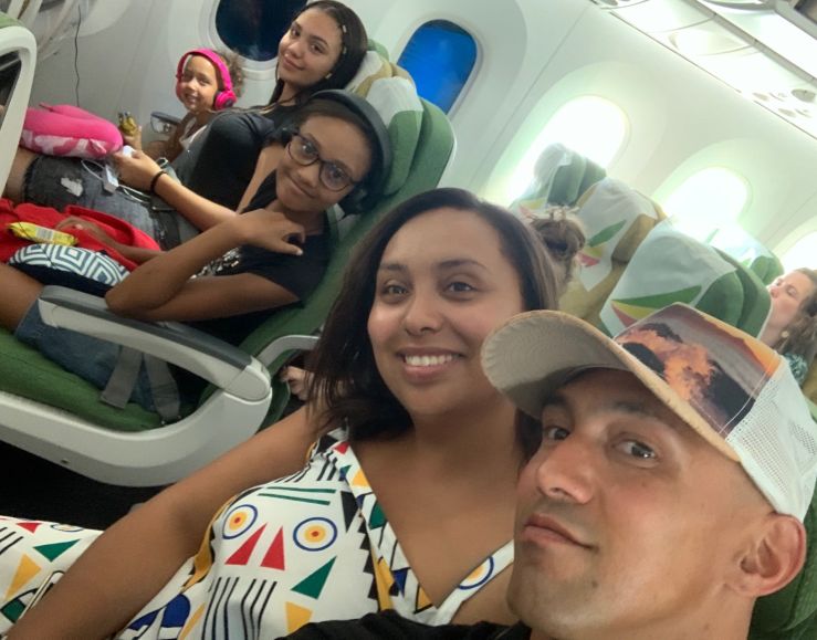 Selfie on plane showing parents and 3 children in background