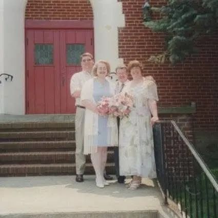 A newly married married couple pose with their wedding party outside the church