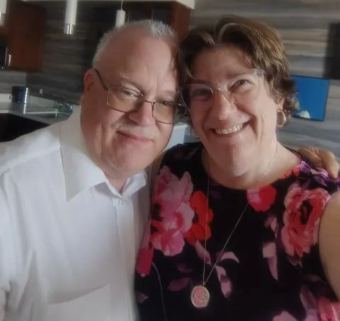 A proud husband and his beaming wife pose together on their 24th anniversary
