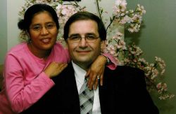 A woman in pink wraps her arms around her smiling man
