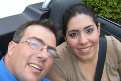 A couple ride in a convertible and smile together while looking up
