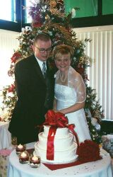 Happy couple cut wedding cake in front of Christmas tree